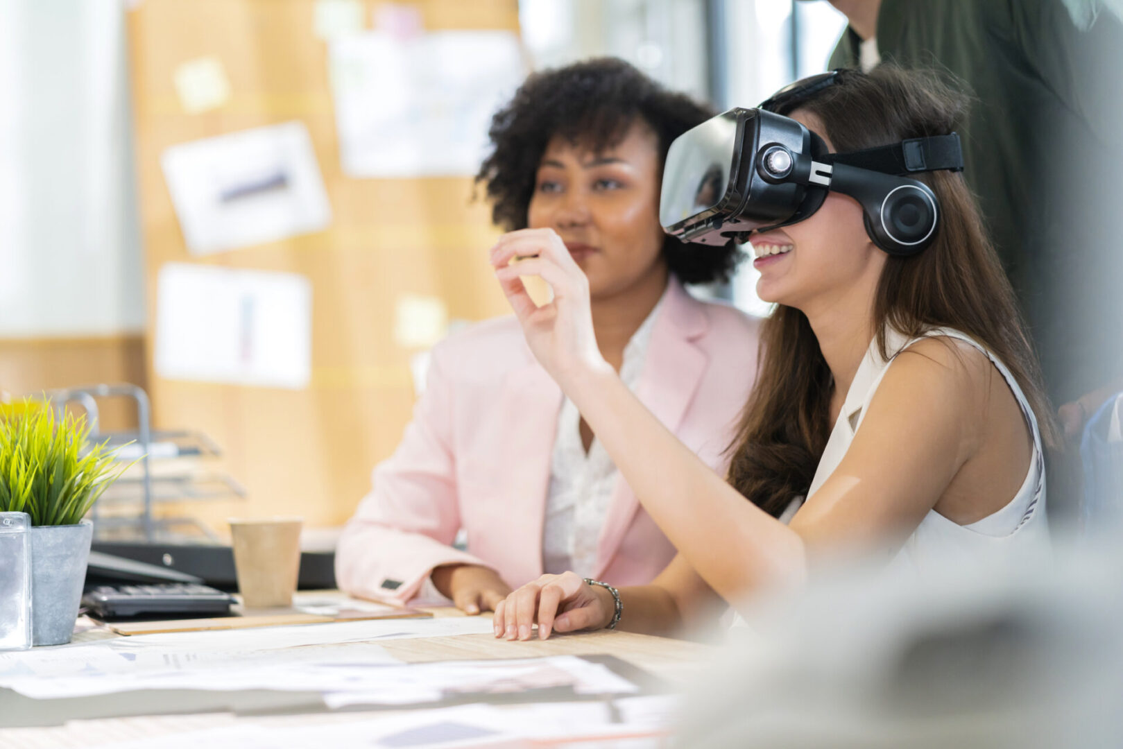 group of millennial male and female multiethnic using vr goggle to test metaverse meeting system cheerful and smiling,office friend standing discussion together next to window office background Woman using VR headset in office meeting.